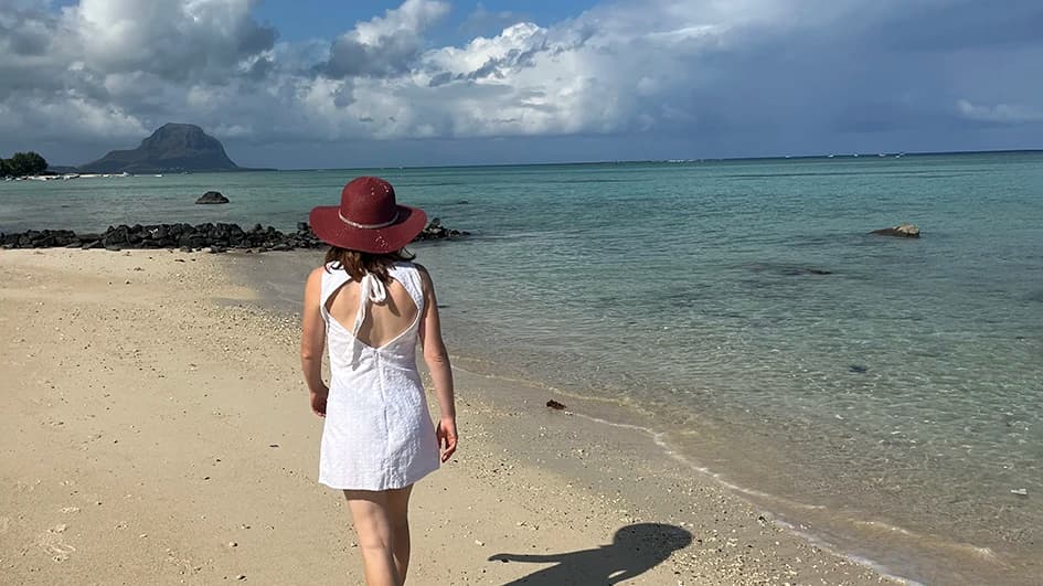 un digital nomad marche sur la plage, face au lagon de maurice.