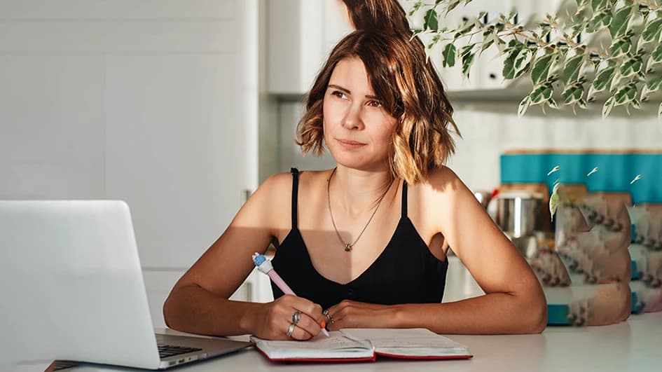 Une femme prend des note lors de sa recherche d'idée pour la création de son logo