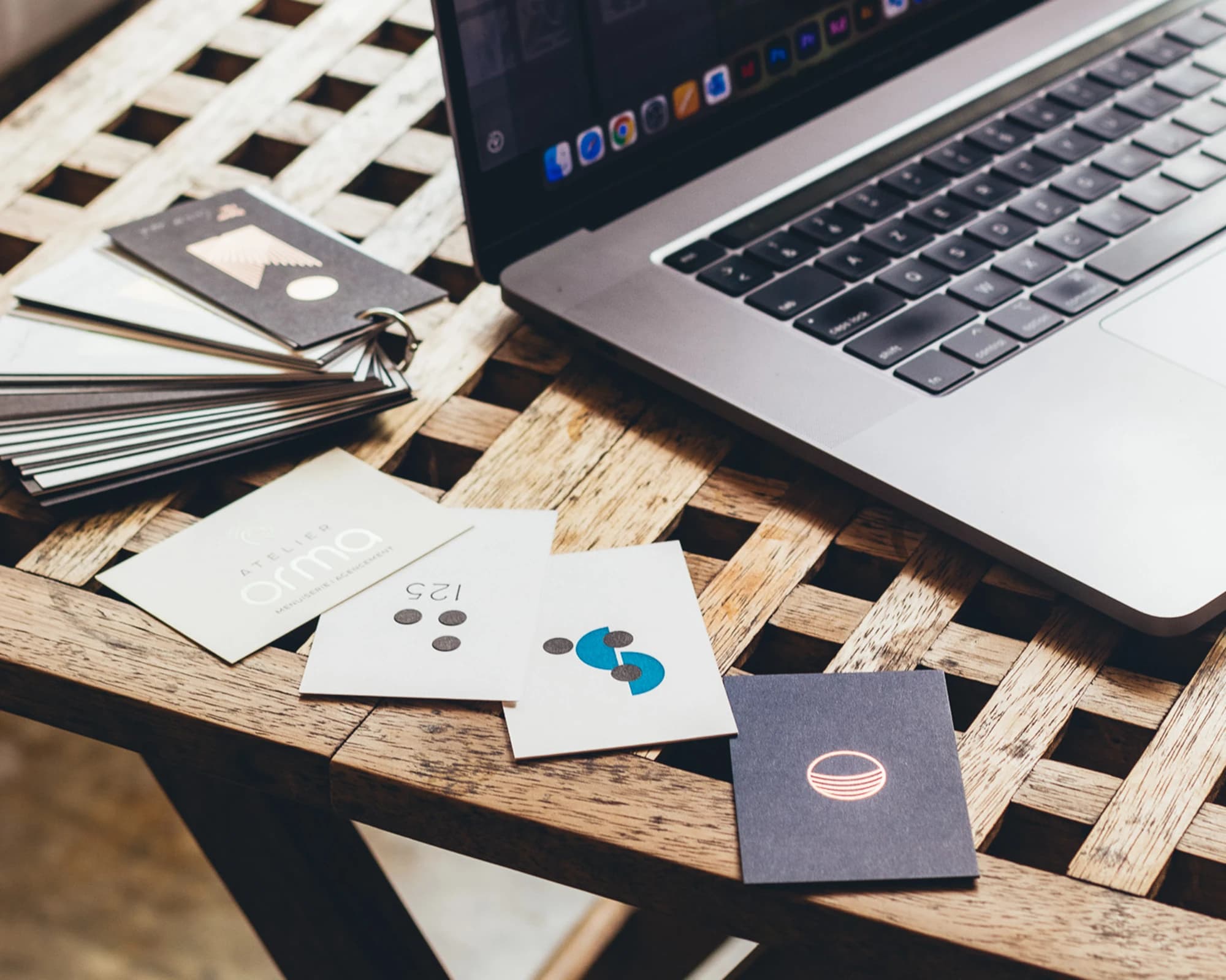 Cartes de logos étalées devant un ordinateur portable : le travail de refonte d'identité visuelle au studio