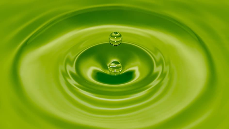 Goutte d’eau tombant dans une eau vert anis et formant des ondes concentriques, symbole de fraîcheur et de nature