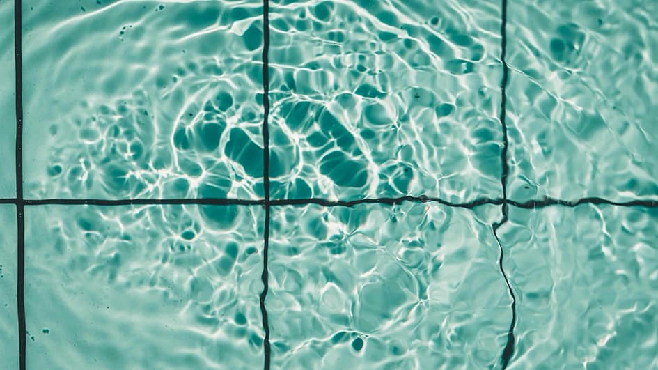 Eau turquoise ondulant sur le carrelage d'une piscine, reflets de lumière dans une teinte bleu aqua