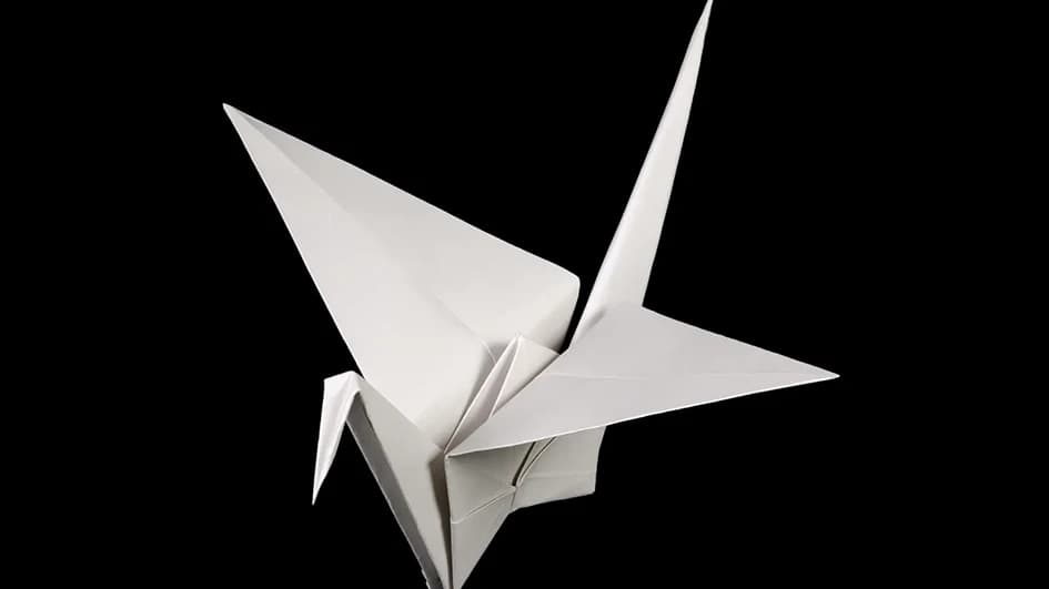 Grue en origami pliée dans un papier blanc épais sur fond noir, illustration de la tenue et de la qualité perçue d'un fort grammage