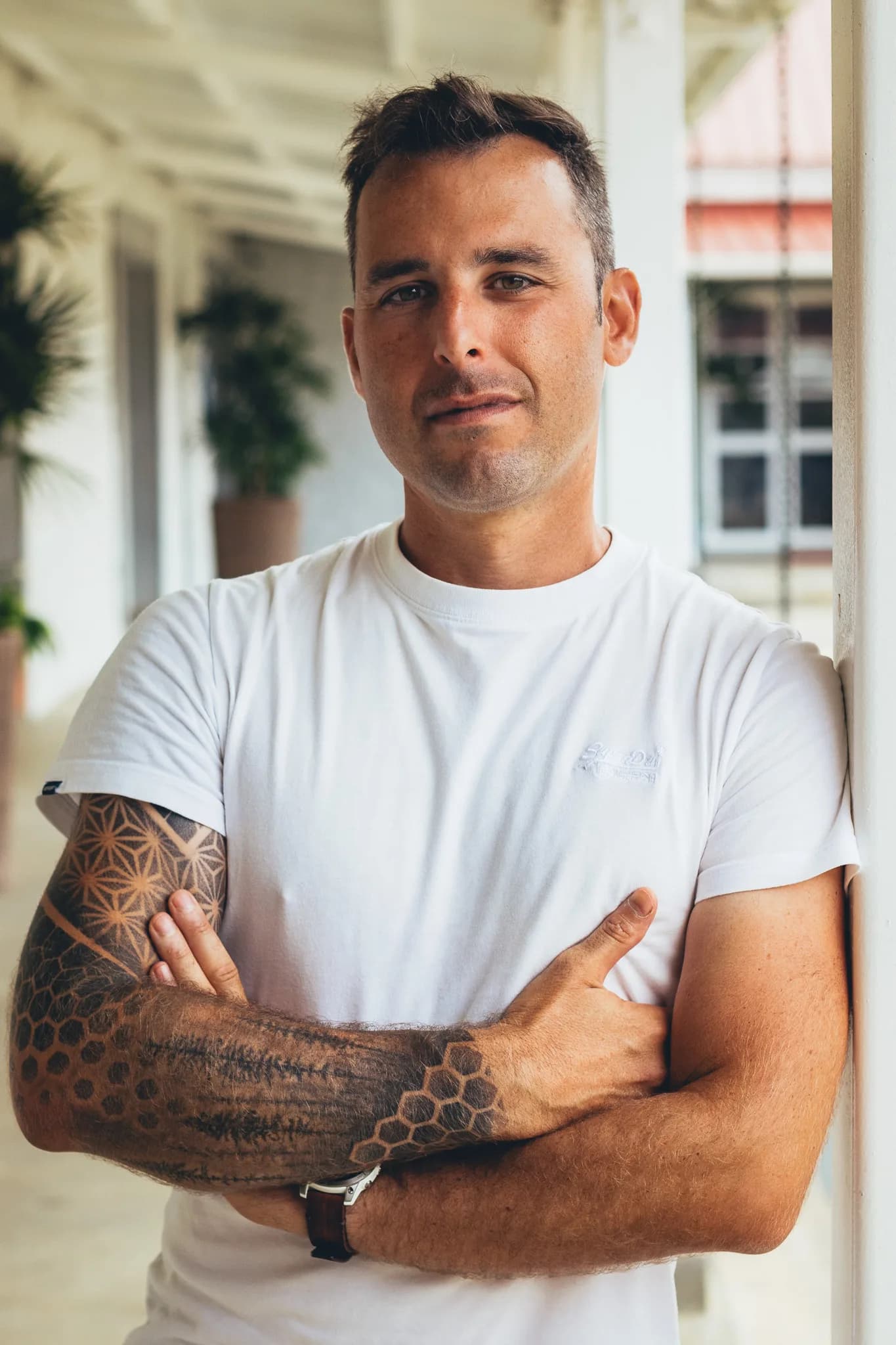 Clément Chappron, développeur full-stack alias L’enfant Sauvage, bras croisés en tee-shirt blanc sous une varangue à l’île Maurice