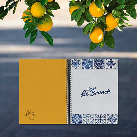 Menu du brunch Chez Marion à spirale : couverture « Le Brunch » bordée d'azulejos et page jaune au citron dessiné