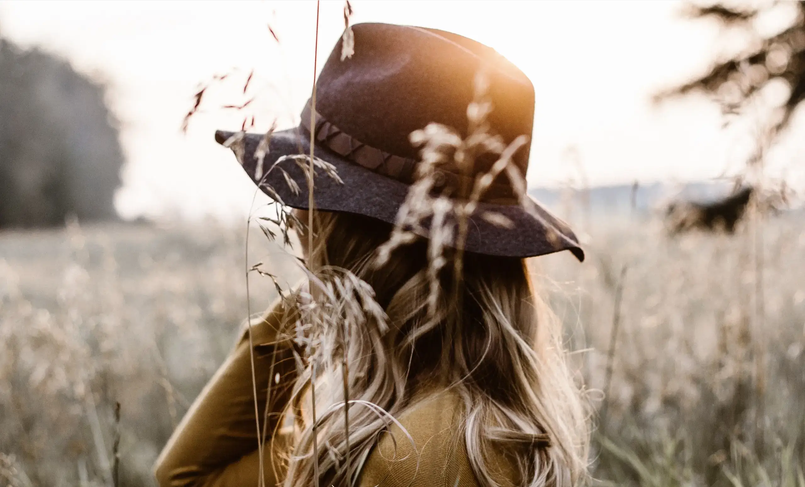 Femme au chapeau de feutre dans les herbes hautes, photo d’ambiance de l’identité Mamma Cramée par le Studio Citron Sorbet, graphiste à Nantes