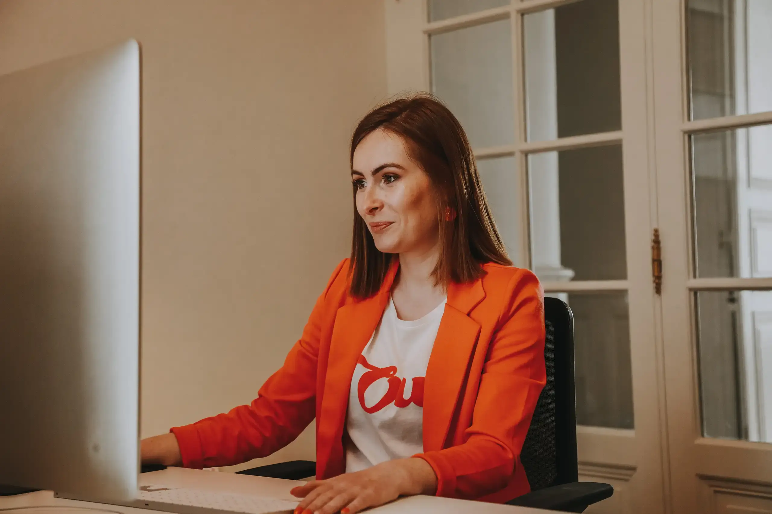 Fanny Métivier, graphiste du Studio Citron Sorbet à Nantes, en veste orange au travail devant son écran d'ordinateur